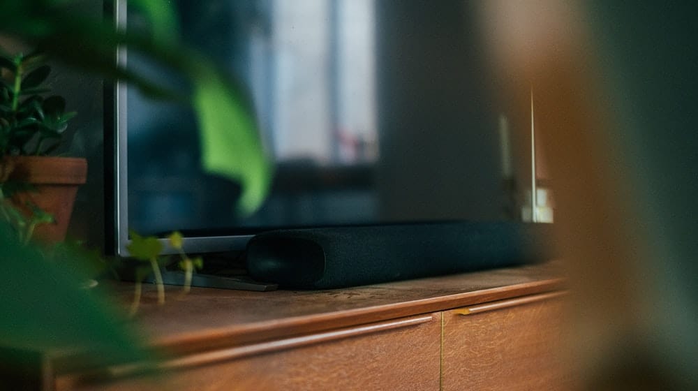 Soundbar op een houten kastje onder een tv.