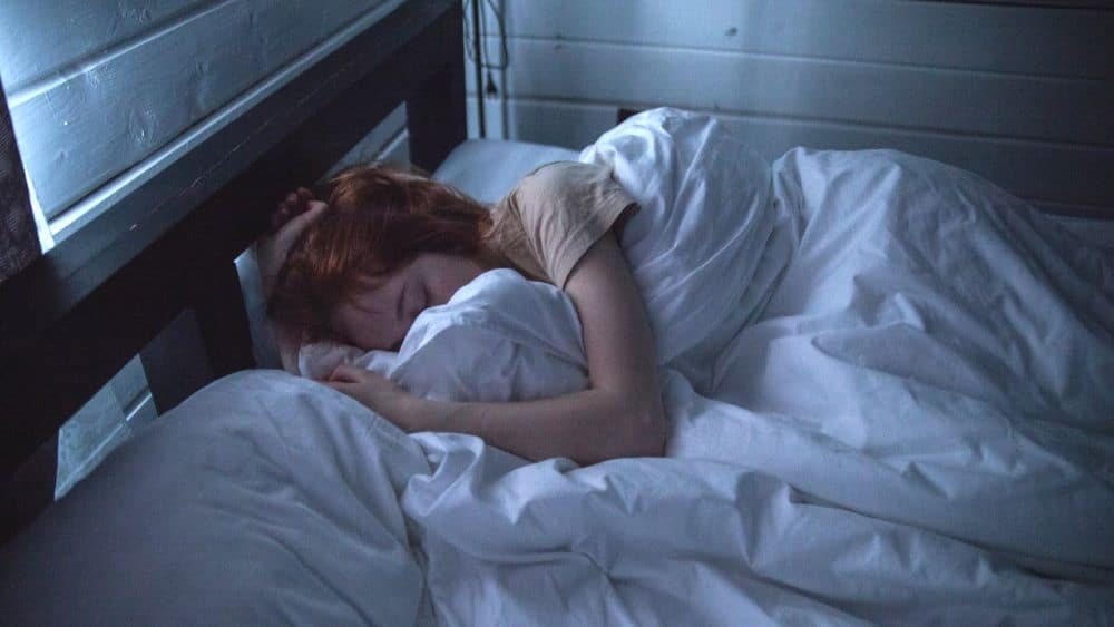 Vrouw slaapt in bed met witte dekens en kussens