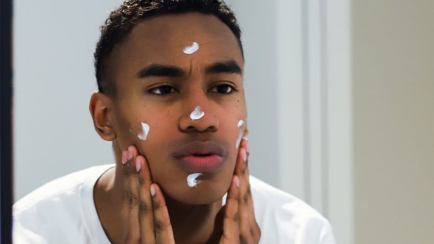 Afbeelding van iemand die moisturizer op zijn gezicht smeert. 