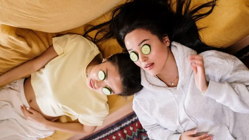 Twee vrouwen liggen en hebben komkommer op de ogen